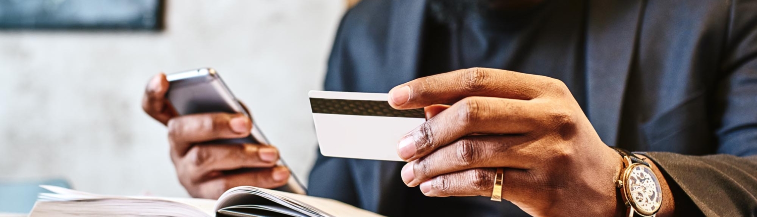 Image of a business person holding a phone and using a credit card.