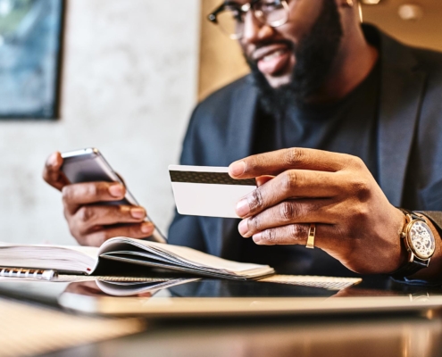 Image of a business person holding a phone and using a credit card.