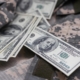 Image of money laying on top of a camouflage uniform.