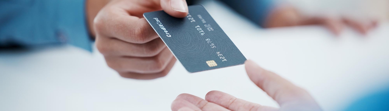 Image of a business person handing out a new credit card.