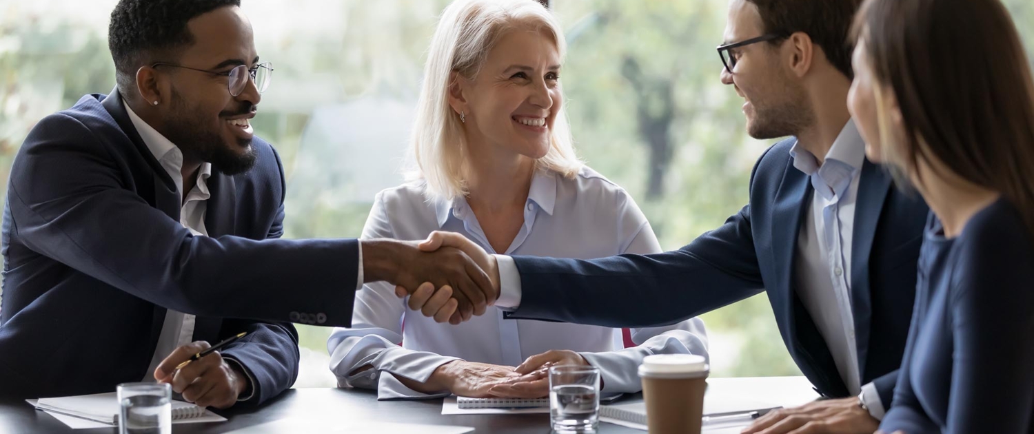 Image of two business people shaking hands in a meeting.